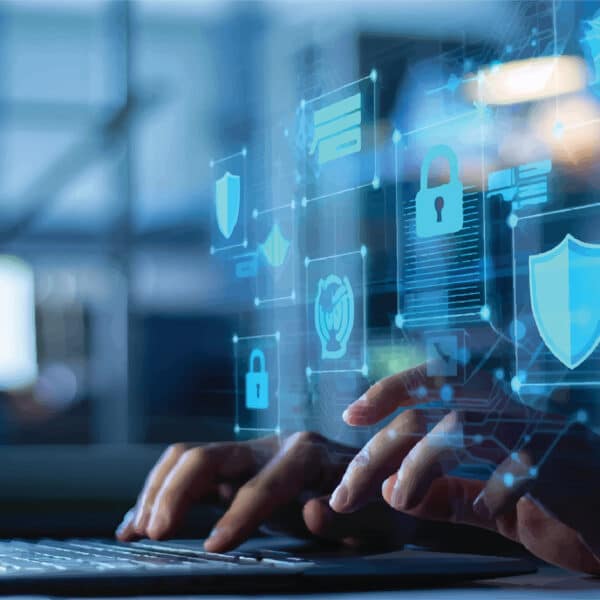 Hands typing on a keyboard with holographic cybersecurity icons like locks and shields, representing data protection in an office.
